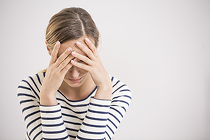 Women holding forehead in hands looking down